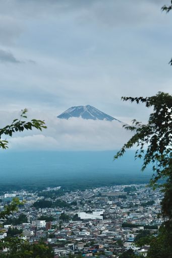 A city nestled beneath cloudy skies with distant mountains: Mt Fuji