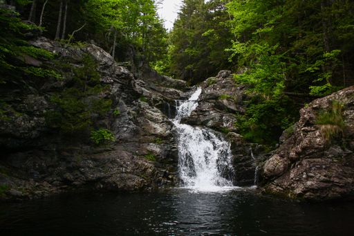 The scenic Memel Falls in New Brunswick cascading through lush forest with rocks and green foliage