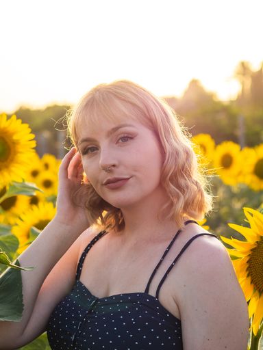 A portrait of a pretty young woman in a summer dress posing in the field of sunflowers