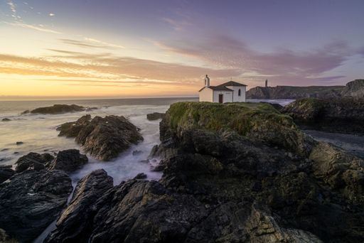The Hermitage of Virgen del Puerto and lighthouse of Valdovino in Galicia, Spain, during a beautiful sunset