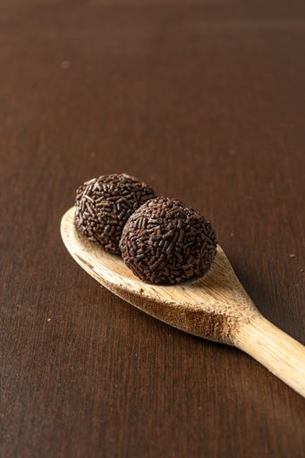 A Brazilian brigadeiro over a wooden spoon
