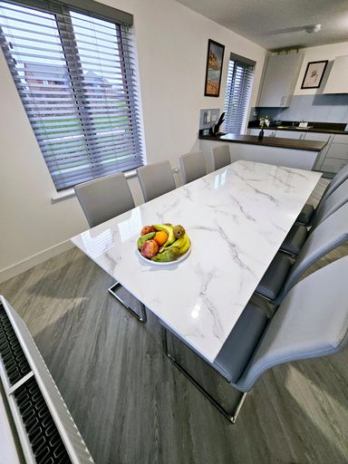 White marble table with four gray chairs and a bowl of fresh fruit on top