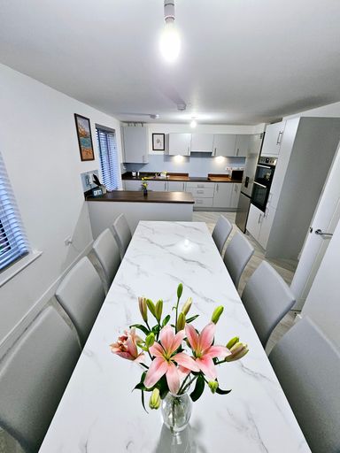 Dining table set for eight with chairs and vase of flowers