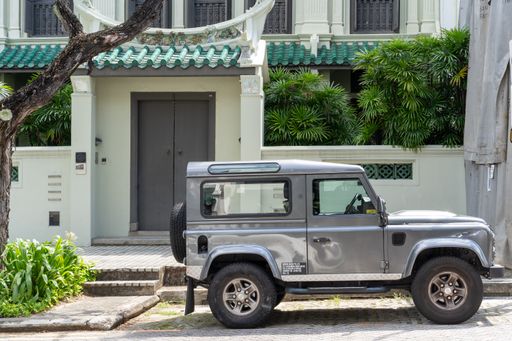 A parked jeep in front of a white building with a green roof
