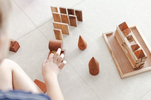 A child playing with wooden building blocks toys in a light minimalist interior