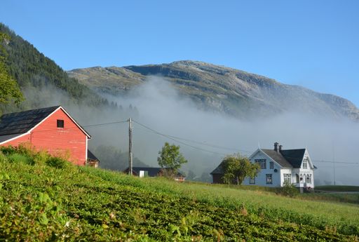 A misty morning view of traditional Norwegian houses in the mountainous countryside near Voss, Norway.