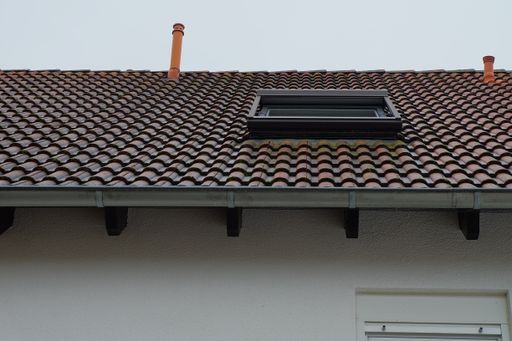 A low angle view of the roof of a building with a dormer on it at daytime