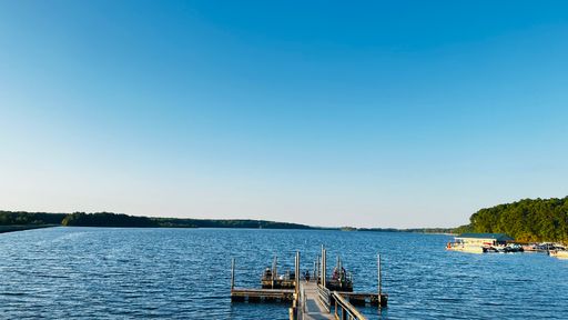 A pier on a serene lake with boats nearby