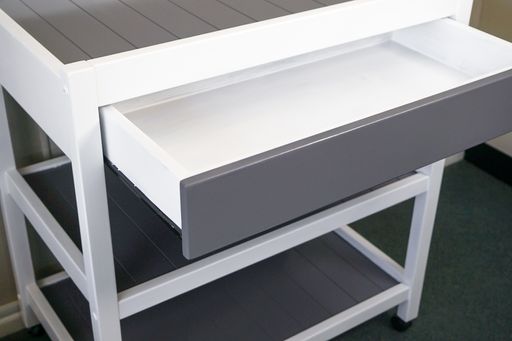 A closeup of a modern white table with a drawer under the lights