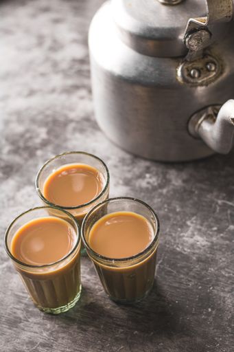 A vertical shot of three glasses of coffee on a kitchen table