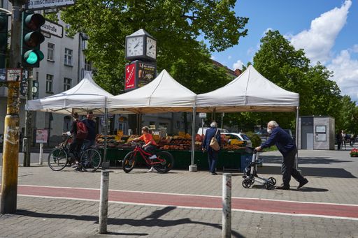Berlin, Germany - May 21, 2021: Berlin cityscape with a market stall for fruit and vegetables on the roadside with customers and passers-by.