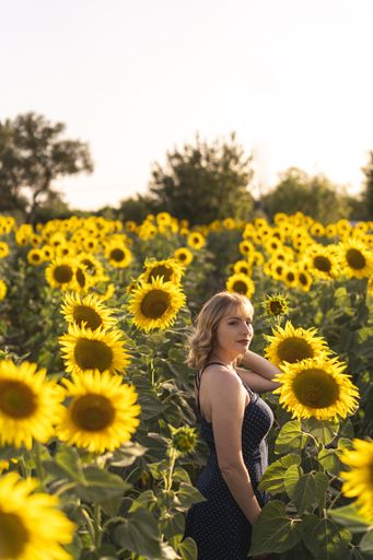 A vertical shot of an attractive Caucasian female posing among the sunflowers on a field in Spain