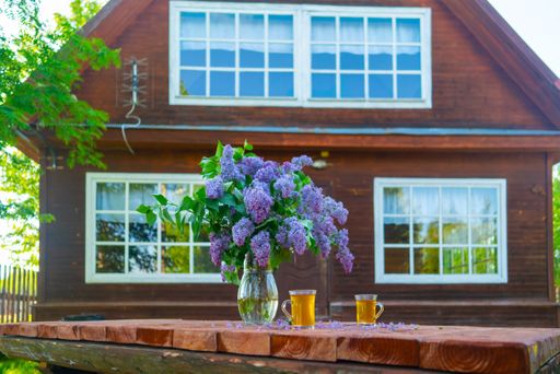 A closeup of a beautiful lilac bouquet in a vase and two glasses of lemonade on a wooden table