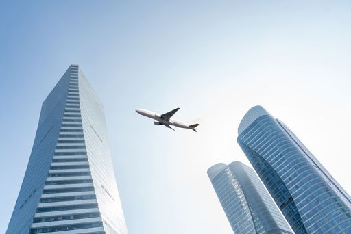 airplane fly over modern office buildings with blue sky, large copy s