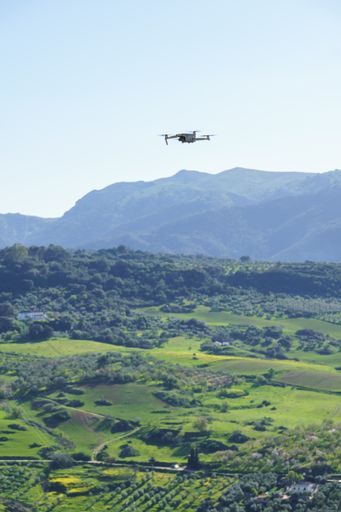drone in flight recording a green mountain landscape with a blue sky