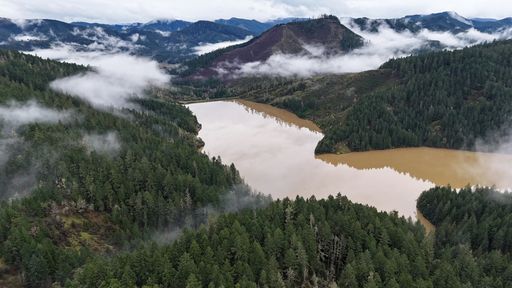 A scenic view of misty mountains rising above a brown river