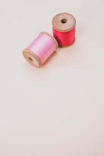 A closeup of pink and red sewing threads isolated on a light background with free space for text