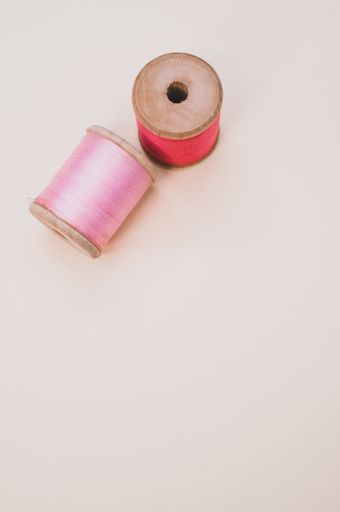 A closeup of pink and red sewing threads isolated on a light background with free space for text