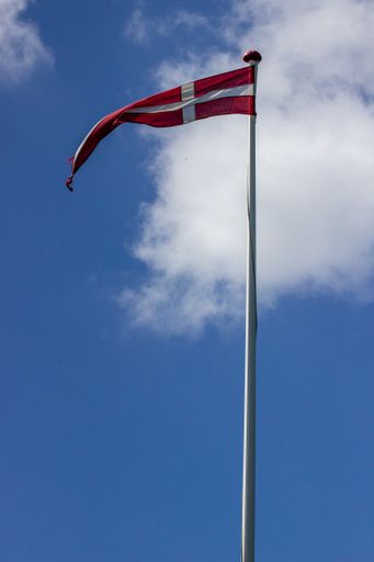 A vertical shot of waving Denmark flag on the blue sky background