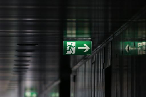Green exit sign along a black aisle