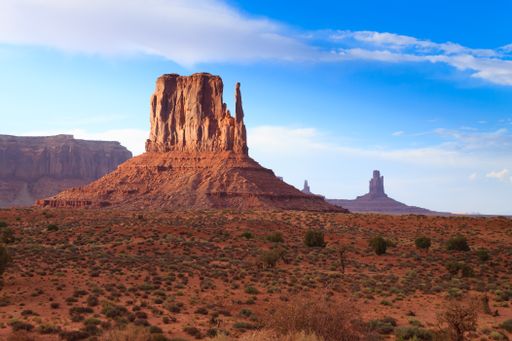 Monument Valley under a clear blue sky in a barren landscape