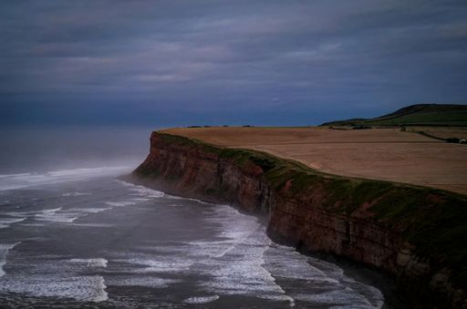 Desolate beach with a towering cliff beside the crashing waves of the ocean