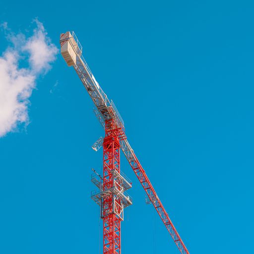 A red construction crane against sky with cloud entering it.