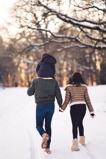 A happy family of three walking hand in hand in the snow