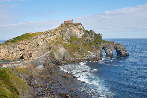 A high angle shot of a cliff peninsula in an ocean on a sunny day