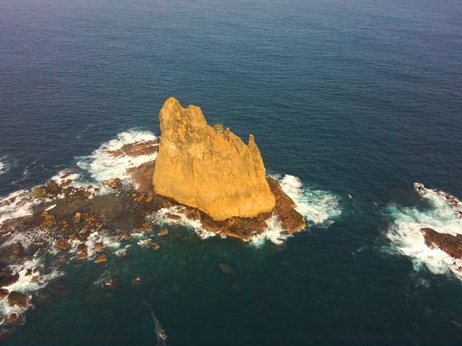 A high angle shot of cliffs near a bright blue sea with waves