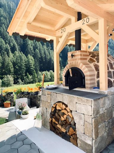 Outdoor pizza oven with stacked firewood for a wood fire