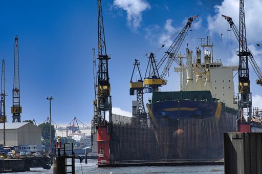 A close-up shot of a big ship surrounded by construction tower cranes