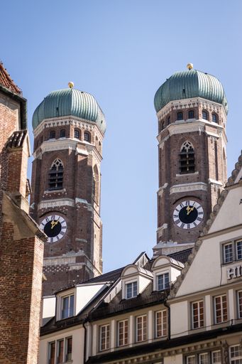 A vertical shot of the two towers of the Marienkirche in Munich between two houses, upper perspective
