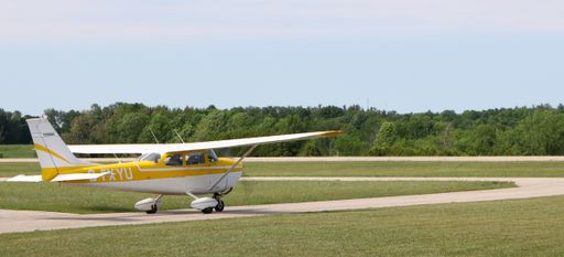 Yellow and white airplane moving toward the runway for take-off in Hanover, Ontario, Canada on a sunny morning
