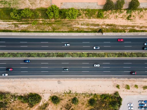 Aerial aerial view of both directions of the highway with cars circulating through it with bushes around it.