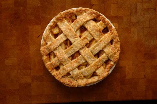 A top view of apple pie with a lattice top on a wooden rustic table