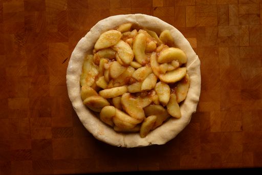 A top view of a pie crust filled with apple slices, ready for baking