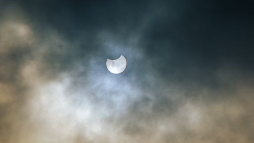 Partial solar eclipse in a cloudy sky over the UK