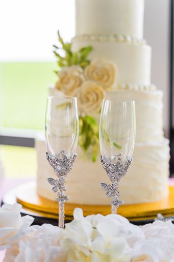 A vertical shot of two glasses next to a four-tier cake