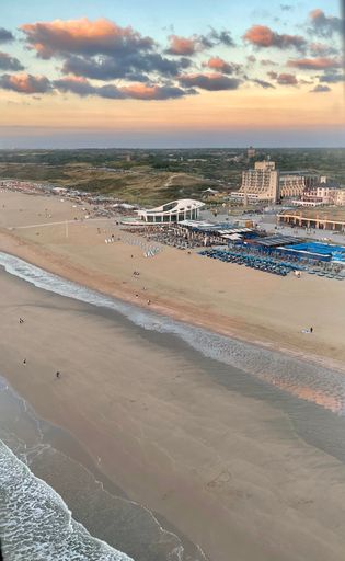 Aerial view of beach and ocean glowing at sunset from airplane window