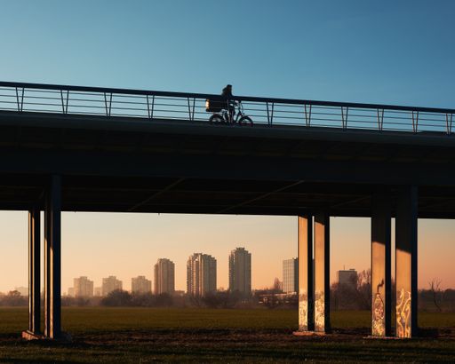A Cyclist rides on overpass with city skyline backdrop, Zagreb, Croatia.