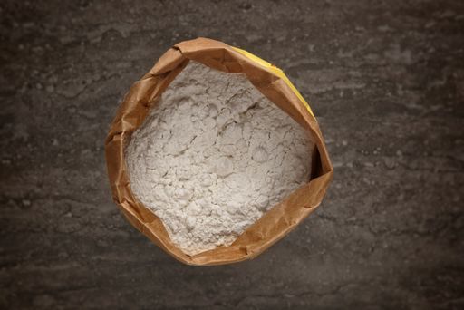 A top view of a brown paper bag of white flour on a table