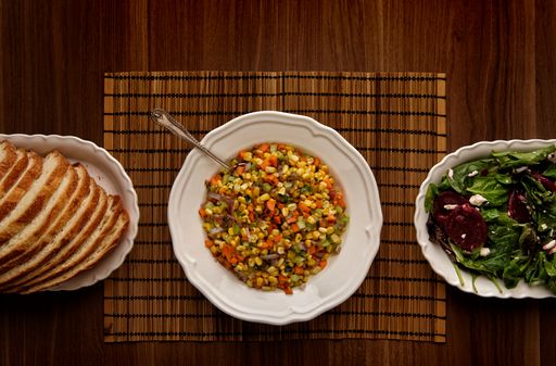 A top view of a spread of roasted vegetables, bread, and salad