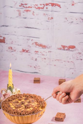 A hand taking a spoon of delicious lucuma mousse with chocolate brownies on a table with candelabra