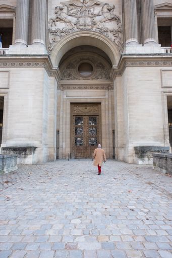 A man walking towards the doors of the Louvre Museum