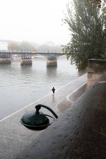 A person running along the quay in Paris on a misty day