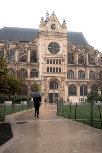 A person with an umbrella walking towards Saint-Eustache Church. Paris, France