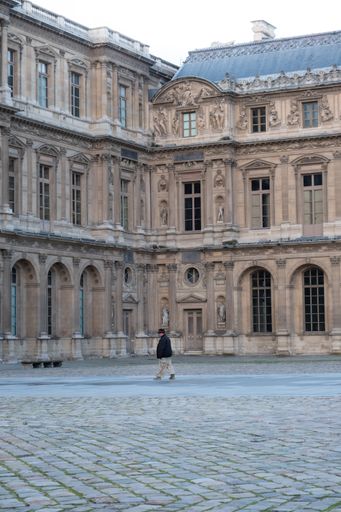 A person in the courtyard of the Louvre Museum