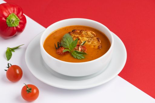 A tomato soup with fresh parsley garnish in a bowl.