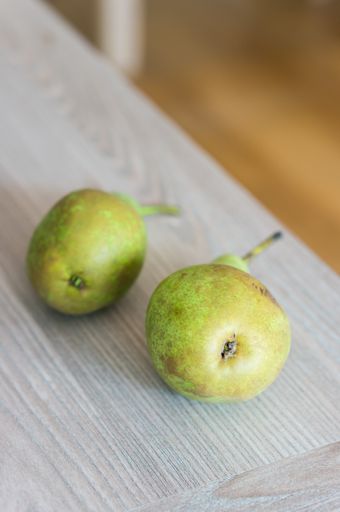 A closeup shot of fresh pears on a wooden table with a blurred background